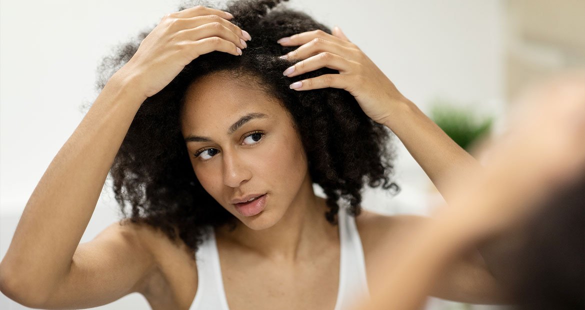 Jovem avalia seu cabelo para identificar qual o melhor óleo de cabelo para seu cabelo